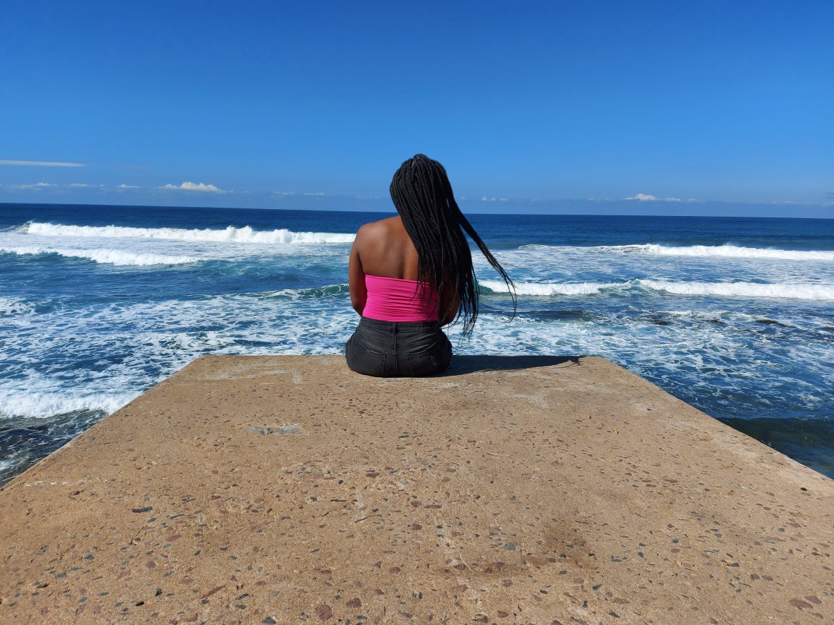 Woman sitting on the beach rock, taking in the breeze