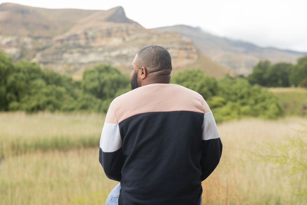 Black man sitting watching the mountains