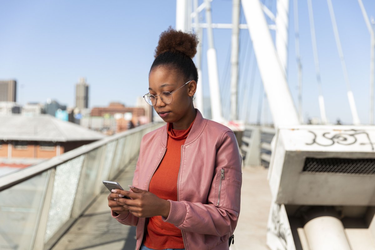 Black woman on a smartphone wearing a pink jacket.