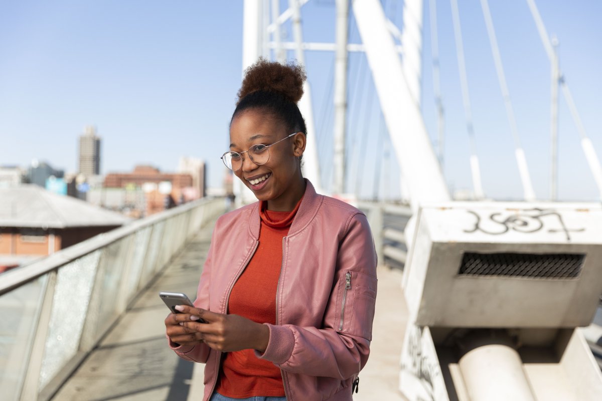 African woman smiling holding a smartphone