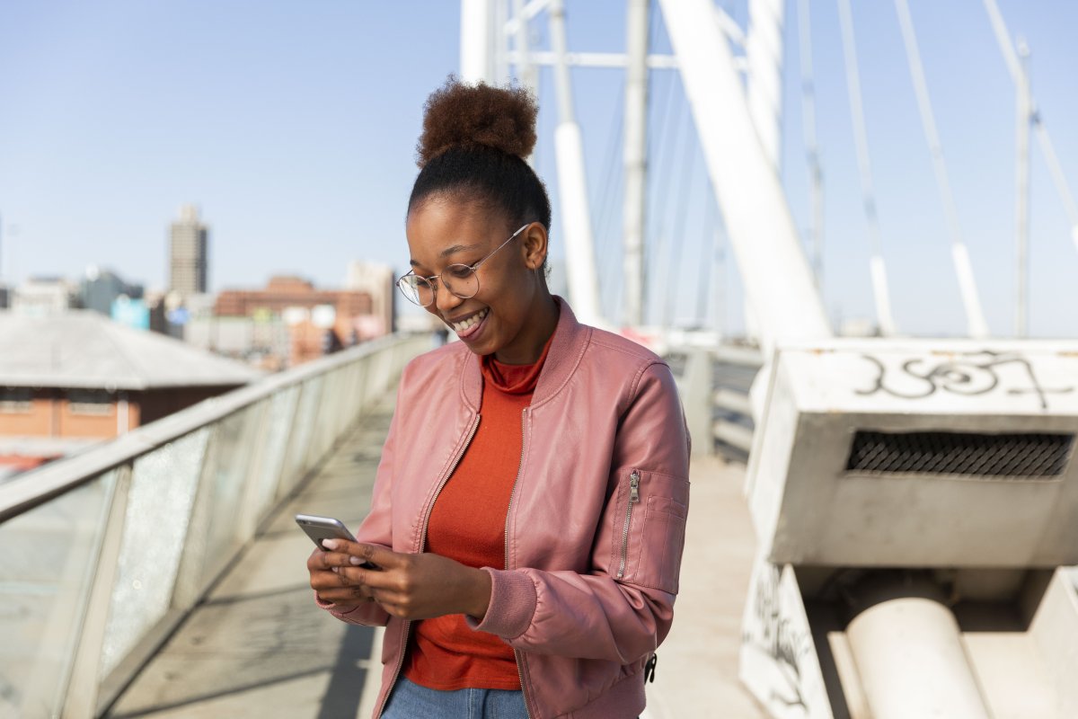 Black woman on Nelson Mandela bridge smiling at smartphone