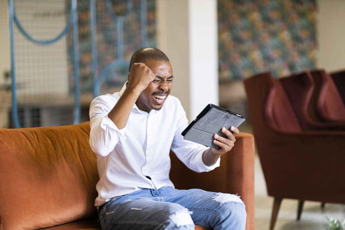 Black man celebrating and looking at ipad