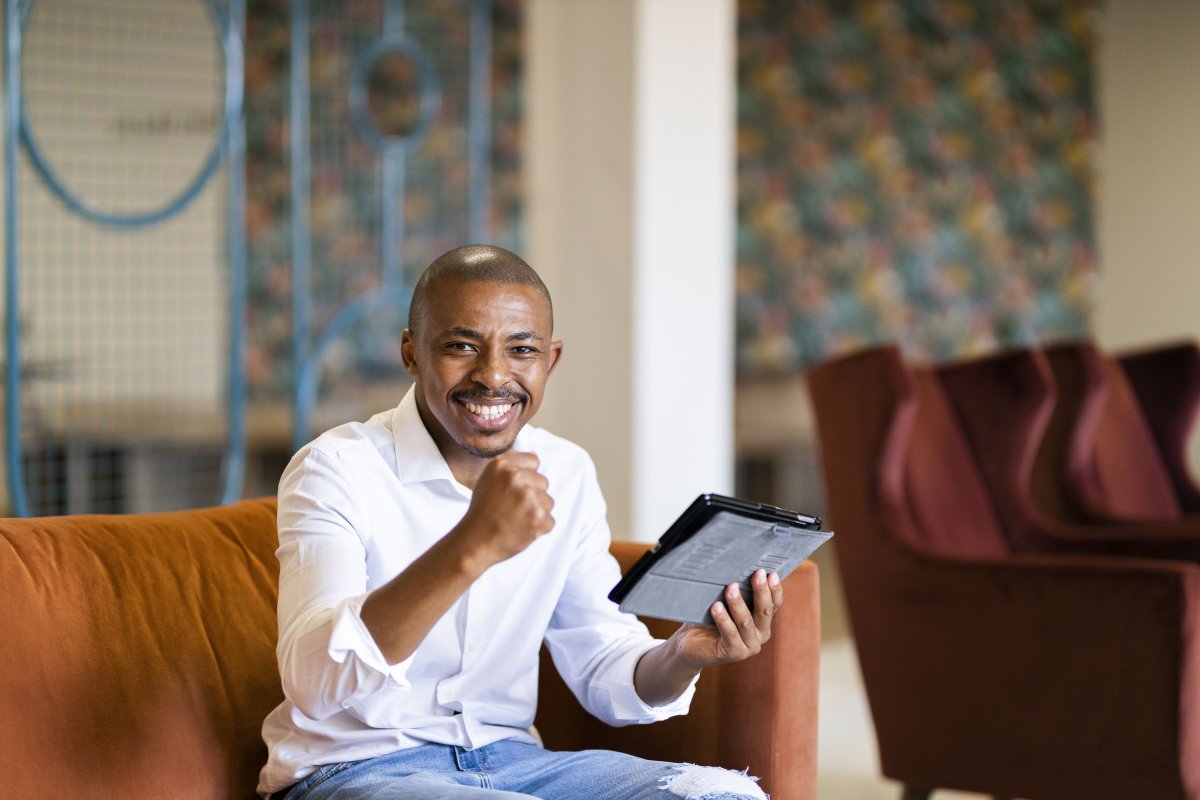 Black business man celebrating while looking at ipad
