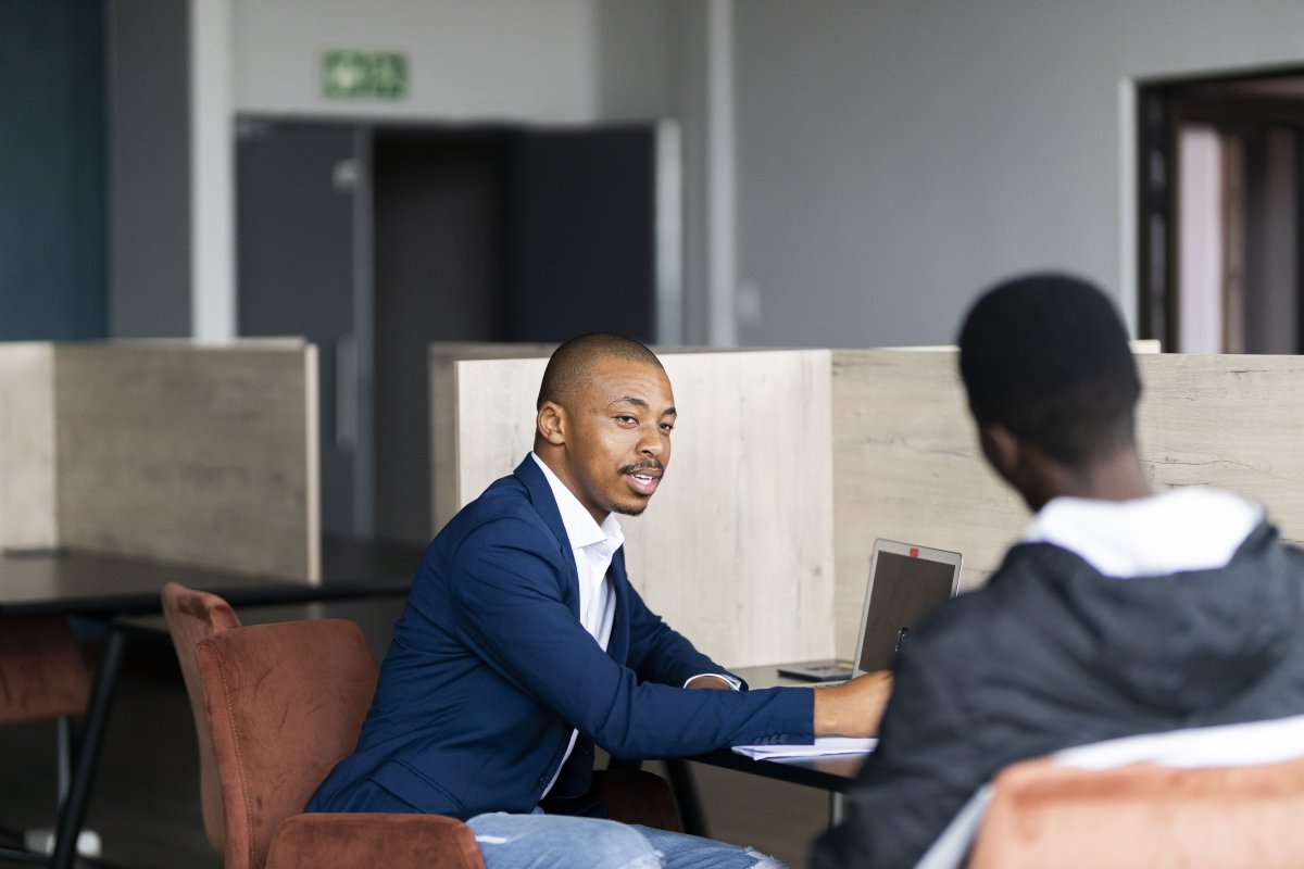 Black business man wearing a suit and talking to his client while smiling