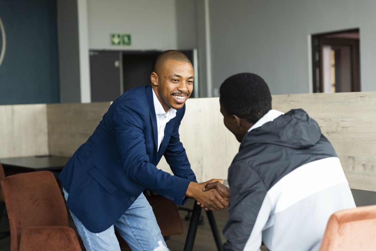 Black business man wearing a suit and shaking hands with a client at the office