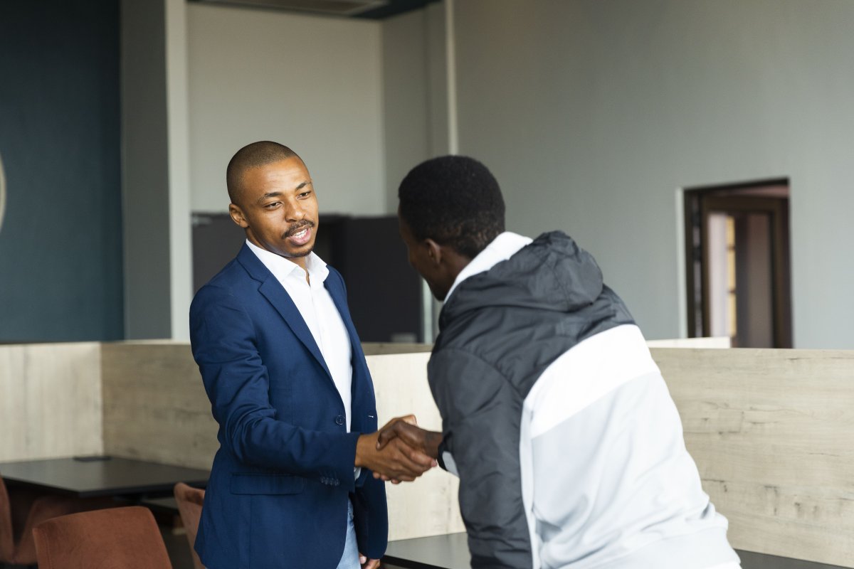 Black business man wearing a suit shaking hands with a client at the office