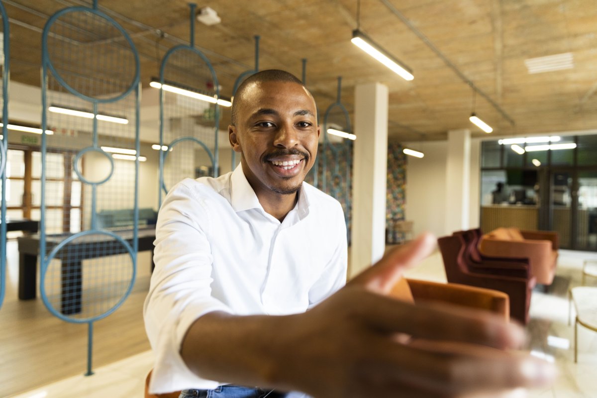 Black business man approaching to shake hands with a client at work while smiling