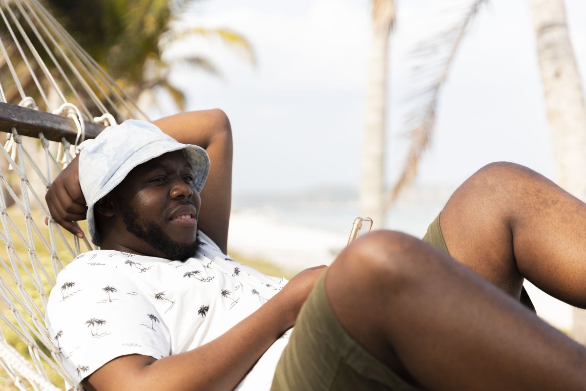 Black man resting on a hammock.