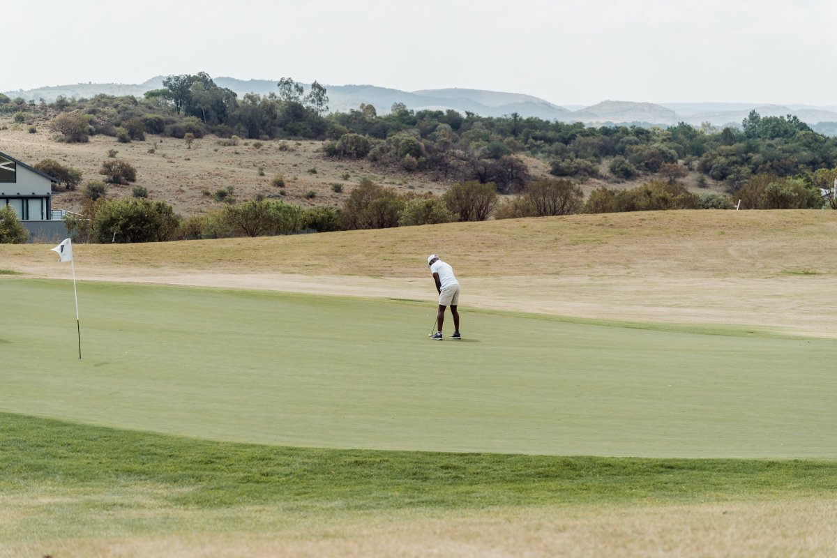 Black male golfer taking a putt on the green