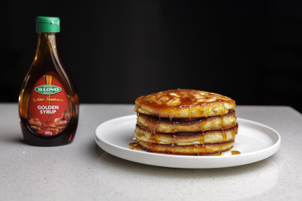 Pancakes on a plate next to golden syrup bottle