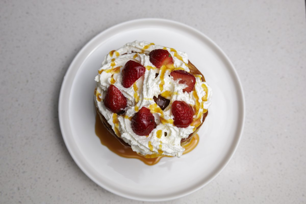 Flatlay of pancakes and cream on a plate with syrup.
