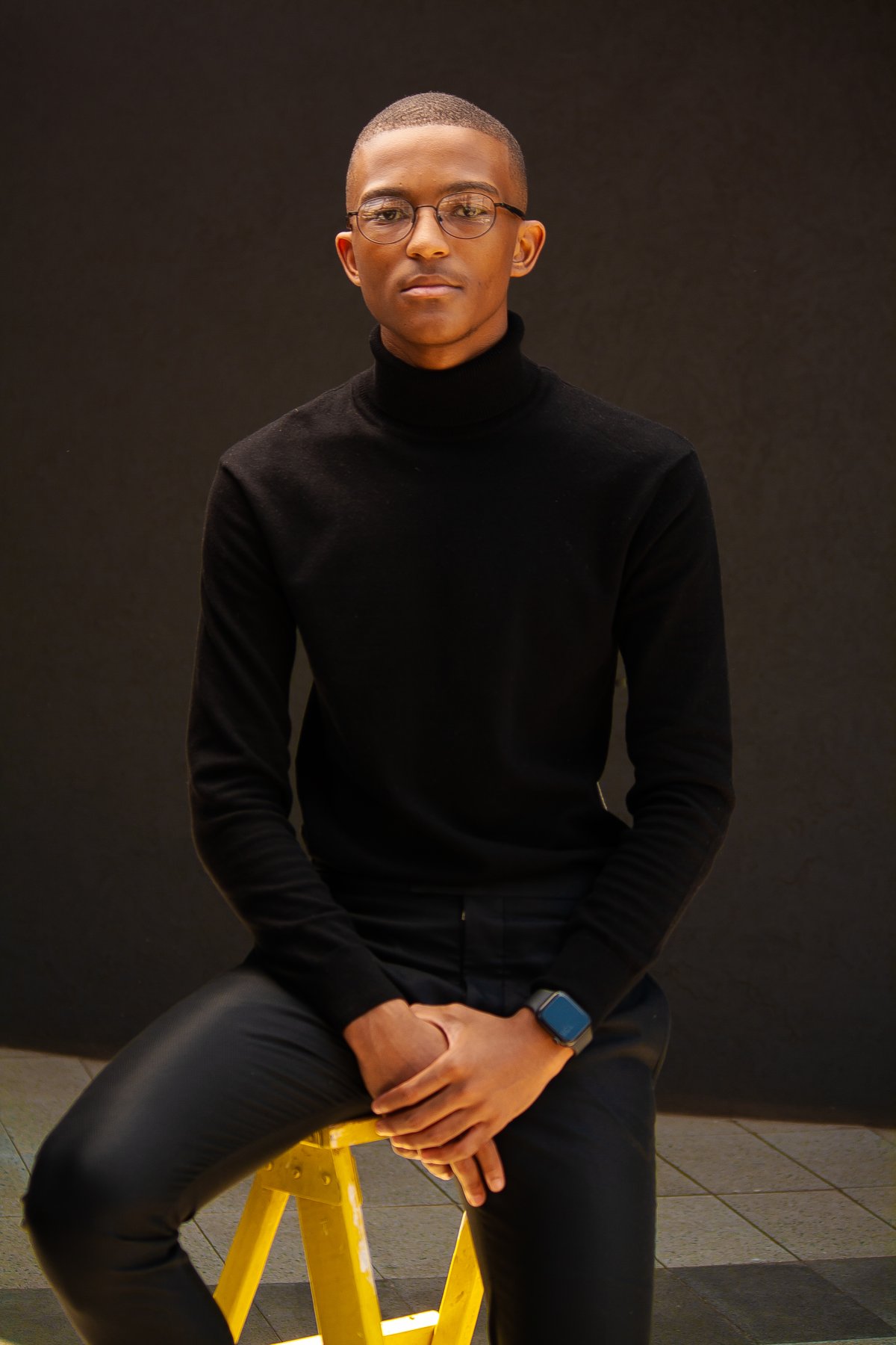 Black man sitting on a yellow ladder