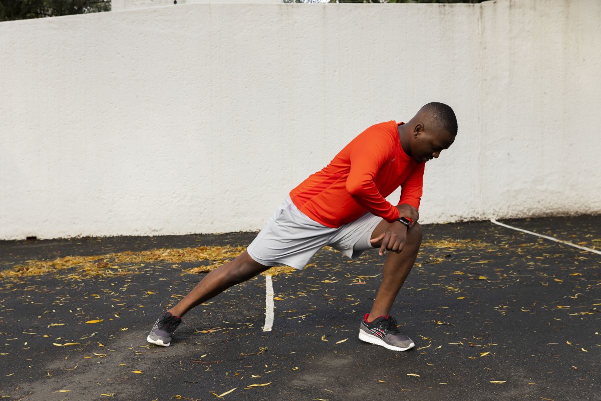 Runner wearing orange top stretching