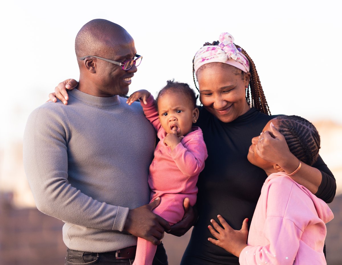 Black family enjoying the sun outdoors smiling, kids wearing pink.