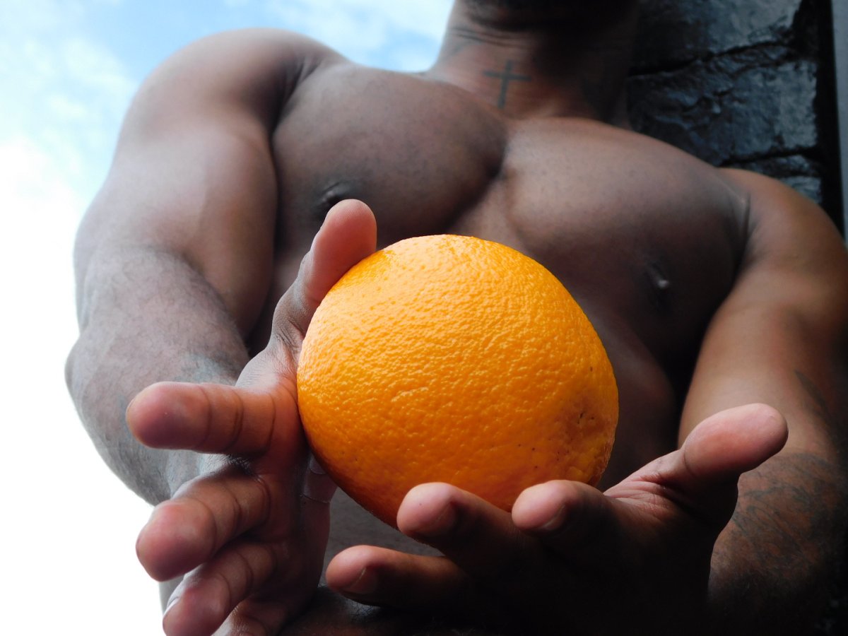 A black man holding an orange