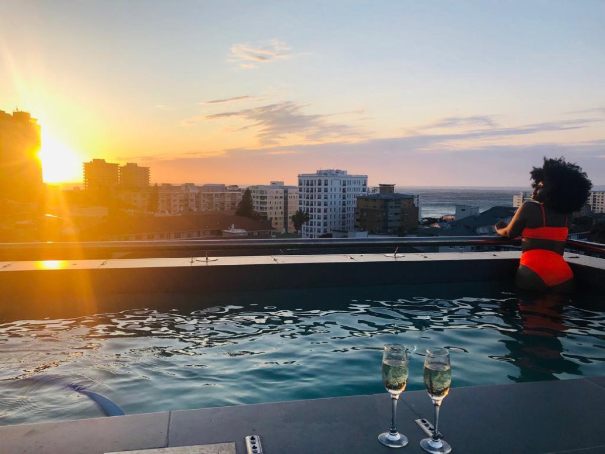 Black woman on a rooftop pool with champagne