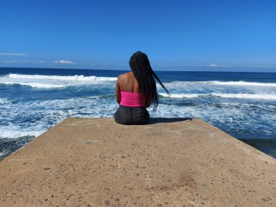 Woman sitting on the beach rock, taking in the breeze