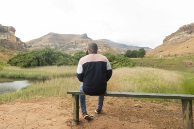 Black man sitting watching the mountains