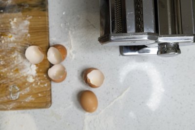 Egg shells on a table next to a pasta maker