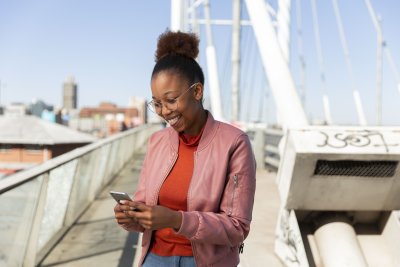 Black woman on Nelson Mandela bridge smiling at smartphone