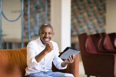 Black business man celebrating while looking at ipad
