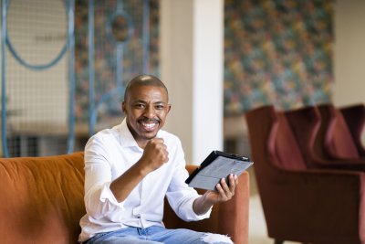 Black business man celebrating while looking at ipad