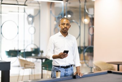 Black man on his cellphone by a pool table at work