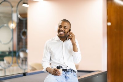 Black man talking on his cellphone by a pool table at work