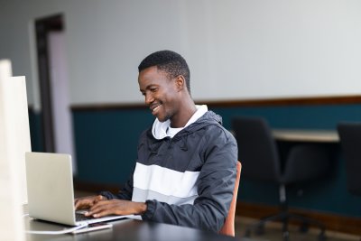 Black man looking at his laptop with a grin on his face