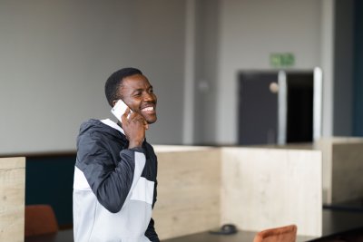 Black man talking on his cellphone at work and smiling