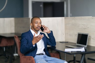 Black business man talking on his phone and wearing a suit at work
