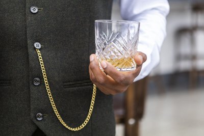 Black hands holding whisky glass