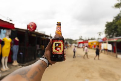 Black hand holding Mozambique beer in the air.