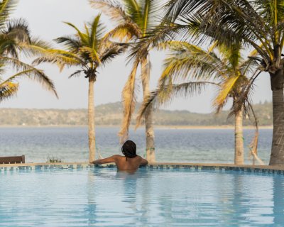 Black woman in a swimming pool overlooking a lagoon.