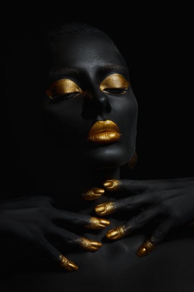 Beauty woman painted in black skin color body art, gold makeup l