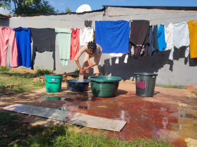 Black woman washing clothes outside her yard.