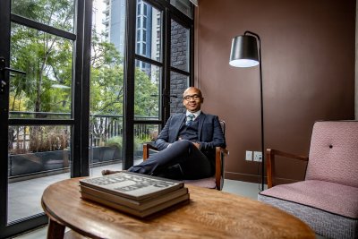 black businessman sitting on a chair in his office with books infront of him