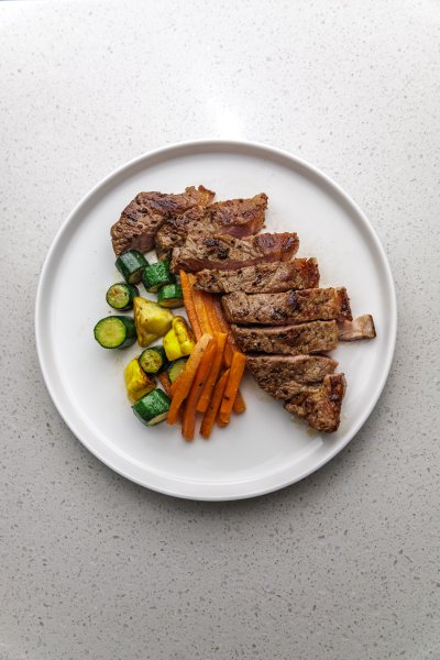 flatlay of well cut steak and vegetables on a plate for dinner