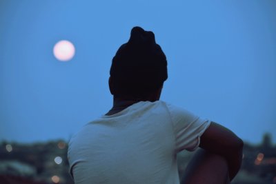 A boy sitting on the fence admiring the sky light