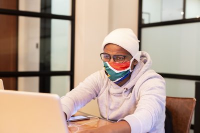 Black man working at the office wearing a mask