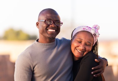 Couple smiling outside with woman holding tightly to the man, happy, outside, summer.