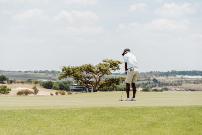 Black male golfer putting on the green with a view