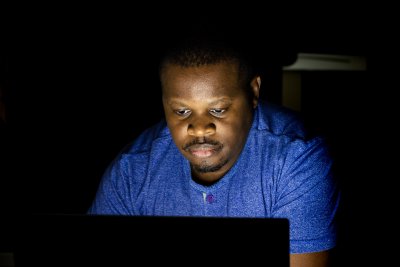 African male looking at laptop screen in the dark