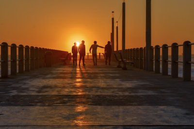 Friends having a morning laugh at the beach while walking towards sunrise direction