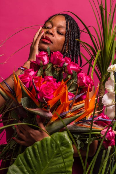 Black woman posing with pink backdrop and plants
