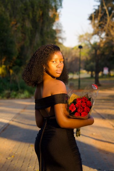 Beautiful black woman posing outside with red roses